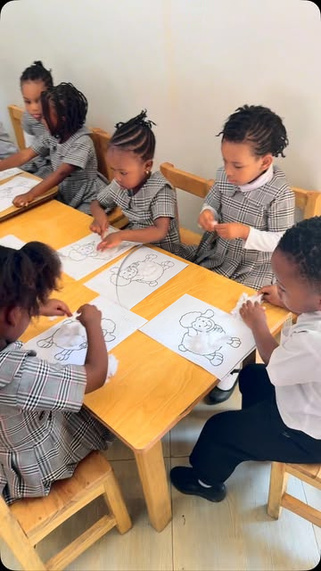 Learners drawing and working together around a classroom table